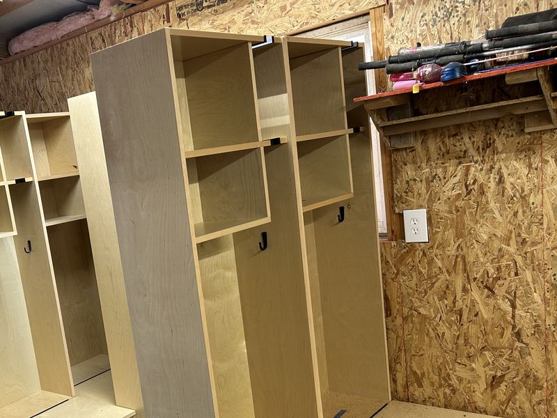Row of finished lockers with hooks, hinged bench seats and vents
