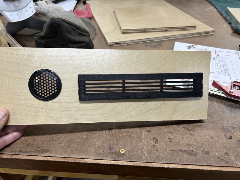 Plywood panel with a store-bought round vent beside a 3D-printed slotted vent