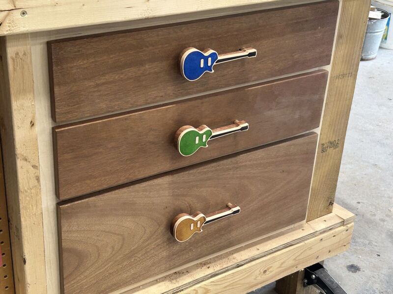 Walnut drawers with guitar-shaped drawer pulls in blue, green and gold