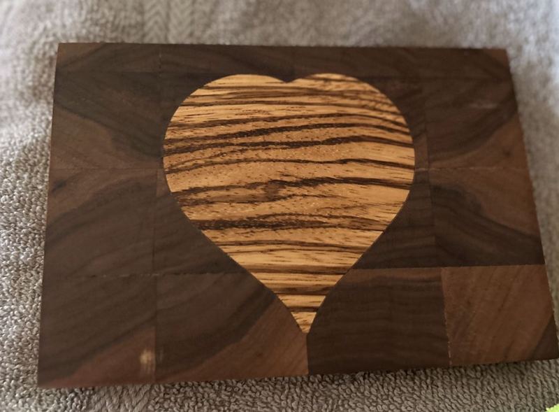 End-grain walnut cutting board with a striped heart inlay