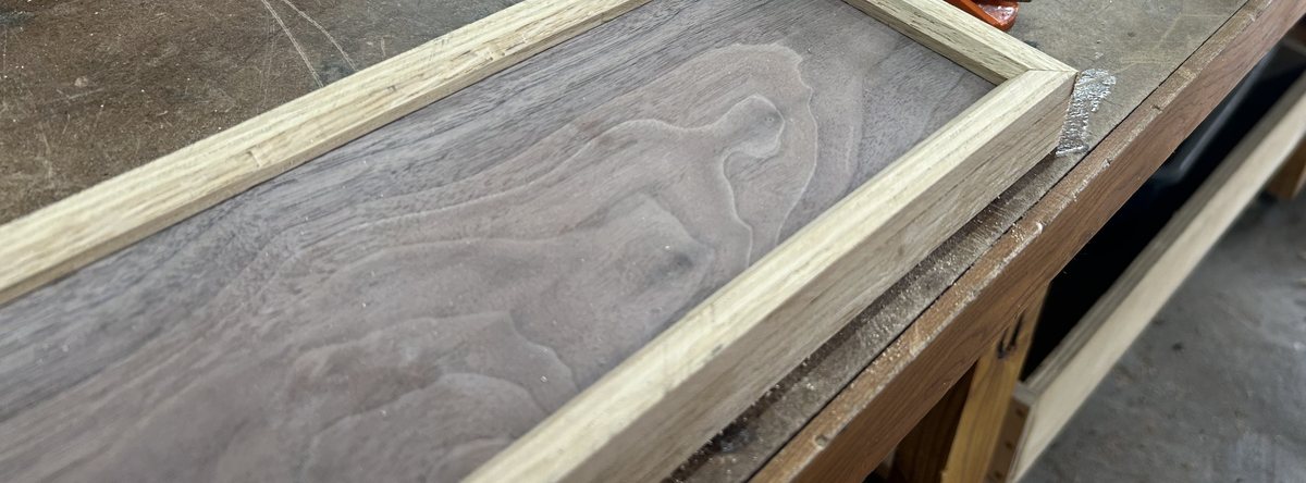 Figured walnut panel fitted into a white oak frame on the workbench
